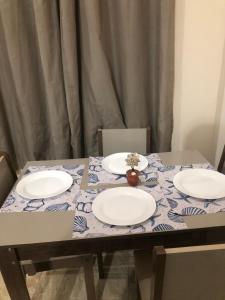 un tavolo con tre piatti e un vaso con dei fiori sopra di Casa unahome a Cabo Frio