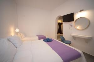 een hotelkamer met twee bedden en een spiegel bij Markakis Studios Fira Town in Fira +83 foto's