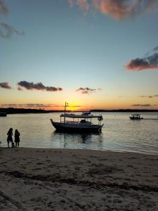a boat in the water with people standing on the beach at Coração do Mar in Cayru