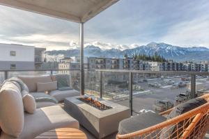 a living room with a couch and a fireplace on a balcony at Cedar Vista - condo with stunning mountain views in Revelstoke