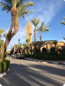 a building with palm trees in front of a street at Ryad Lalla khadija in Marrakech +51 photos