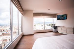 a bedroom with a bed and large windows at Majestic Hotel in Ipiales