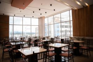 a dining room with tables and chairs and large windows at Majestic Hotel in Ipiales