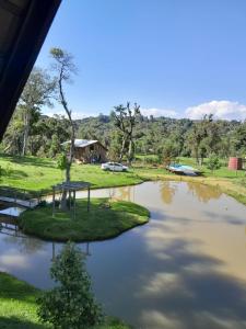 Blick auf einen Teich mit einem Haus im Hintergrund in der Unterkunft Refúgio Serrano in São Francisco de Paula