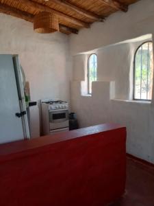 a kitchen with a stove and two windows at Nativas Cabaña Amarilla in Senador Pérez