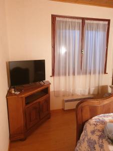 a living room with a television on a wooden cabinet at Logement du Bois de Chaubon in Fillinges