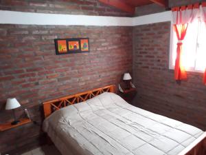 a bedroom with a brick wall and a bed at Cabañas Abú in Trapiche