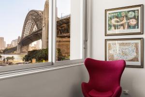 a red chair sitting in front of a window at Opera House Retreat - Opera House & Bridge View in Sydney