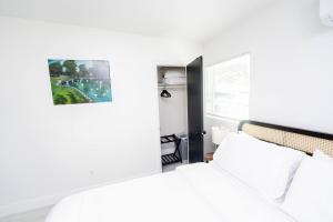 a white bedroom with a bed and a picture on the wall at Close to the Action, Peaceful When You Return in Orlando