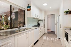 een keuken met witte kasten en een spoelbak bij Rosebud Beach Haven in Rosebud