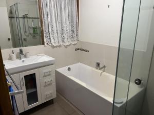 een badkamer met een bad, een wastafel en een spiegel bij Rosebud Beach Haven in Rosebud