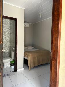 a bedroom with a bed and a bathroom with a toilet at Casa Aiyra in São Miguel dos Milagres