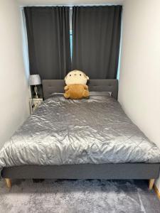 un orsacchiotto seduto su un letto in una camera da letto di Spacious Cosy Apartment a Søborg
