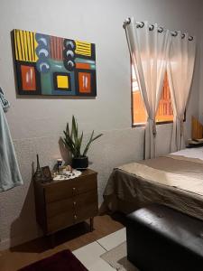 a bedroom with a bed and a dresser and a window at Villas House in Pirenópolis
