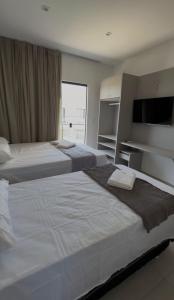 zwei Betten in einem Hotelzimmer mit großem Fenster in der Unterkunft Flat em Barra Grande com piscina in Barra Grande