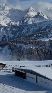 a building in the snow with a snow covered mountain at Sympathique T3 in Aiguebelle +4 photos