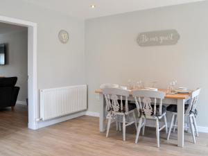 een eetkamer met een tafel en witte stoelen bij Crofthouse - Uk43405 in Wigtown
