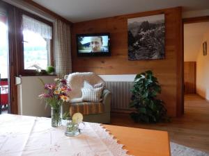 een woonkamer met een tafel en een tv aan de muur bij III in the Anton house in Obermaiselstein