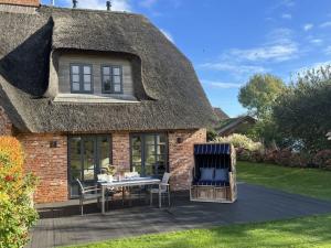 una casa con tetto di paglia, tavolo e sedie di Object 77 Nieblum a Goting