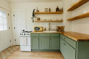 een keuken met groene kasten en een spoelbak bij Rose Park Cottage in Community Medical Center Heliport