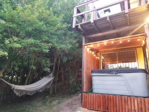 a hammock in front of a building with a hot tub at Cabaña Los Pololos in Villa Serrana