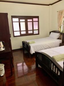 een slaapkamer met twee bedden, een tafel en een raam bij SJ House in Chiang Mai