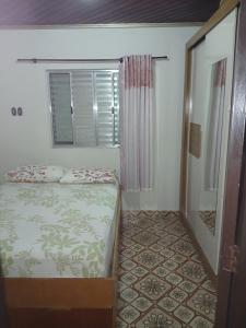 een kleine slaapkamer met een bed en een raam bij Casa azul in Iguape