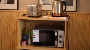a microwave sitting on a shelf with a toaster oven at El Jardin in Puerto Natales