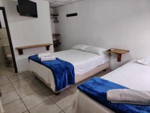 a room with two beds and a flat screen tv at Hostal Darwin in Puerto Ayora