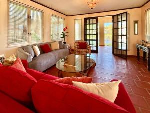 a living room with a red couch and a table at Villa De Palma -Oceanfront community w generator in Sabana +109 photos