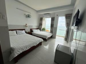 een slaapkamer met 2 bedden, een televisie en een raam bij Vi-vu Hotel Quy Nhơn in Quy Nhon