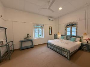 a bedroom with a bed and two windows at 1929 Sudu Colonial House in Ambalangoda