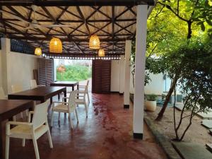 a dining room with tables and chairs and trees at JAGA HOME in Tangalle