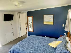 una camera da letto blu con un letto e una televisione di Self-Contained Sleep out a Motueka