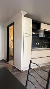 una cucina con mobili bianchi, tavolo e sedie di Charmant studio avec terrasse a Aiguebelle Altre 12 foto