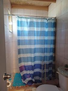 een blauw douchegordijn in een badkamer met een toilet bij Cabañas Sandra Bucalemu Alto in Bucalemu