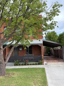 een stenen huis met een hek en een boom bij Rosewood Terrace in Bathurst