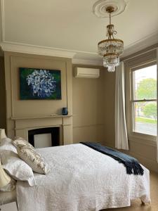 een slaapkamer met een bed, een open haard en een kroonluchter bij Rosewood Terrace in Bathurst