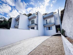 ein weißes Haus mit einer weißen Wand in der Unterkunft Casa Nova e Completa | 2 Suítes com Ar | Área Gourmet | 2 Vagas in Brusque