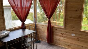 una camera con due finestre con tende rosse di Cabañas a Quemchi