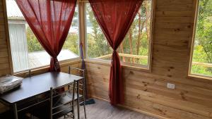 una camera con due finestre con tende rosse di Cabañas a Quemchi Altre 2 foto