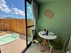 un patio avec une table et des chaises et un bain à remous dans l'établissement Max Carneiros Suítes - Com e sem piscina privativa, à Praia dos Carneiros