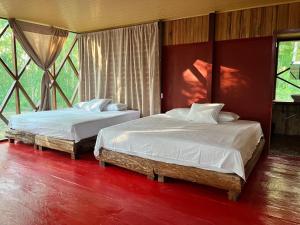 due letti in una stanza con pavimenti e finestre rossi di Tekuna a Leticia