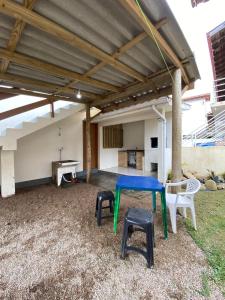 a patio with a table and stools in a yard at Casa aconchegante in Garopaba +3 photos