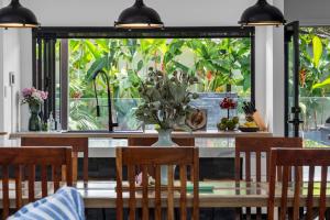 a dining room table with chairs and a vase of flowers at Summit to Sea, Elevated Luxury in Coolum Beach