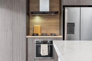a kitchen with a stove and a refrigerator at Summit to Sea, Elevated Luxury in Coolum Beach