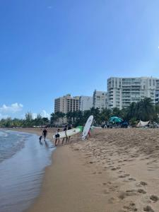 un gruppo di persone che camminano sulla spiaggia con tavole da surf di Aquamarine a San Juan