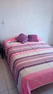 ein Bett mit einer bunten Decke und Kissen darauf in der Unterkunft casa cactus in Acapulco