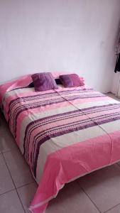ein Bett mit einer rosa und weißen Decke darauf in der Unterkunft casa cactus in Acapulco