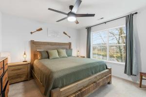 a bedroom with a bed with a ceiling fan and a window at Modern Fishing Lodge 8ppl in Branson